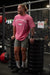 Man in a pink BodyFreaks shirt, grey shorts, and black sneakers